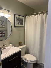 Bathroom with vanity, a shower with shower curtain, a textured ceiling, and toilet