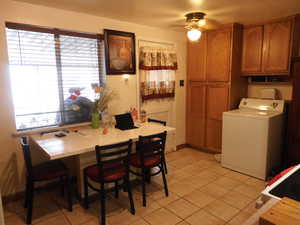 Tiled dining area with ceiling fan and washer / clothes dryer