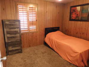 Carpeted bedroom featuring wooden walls