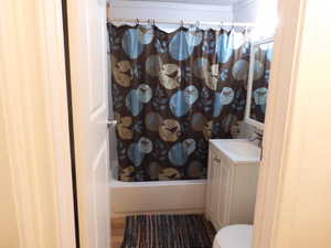 Full bathroom featuring vanity, hardwood / wood-style flooring, toilet, ornamental molding, and shower / bath combo with shower curtain