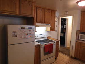 Kitchen featuring light tile patterned floors and white appliances