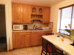 Kitchen with light tile patterned flooring, tasteful backsplash, and sink