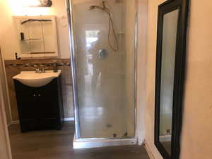 Bathroom with decorative backsplash, hardwood / wood-style floors, vanity, and walk in shower