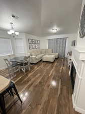 Living room featuring a notable chandelier, dark hardwood / wood-style flooring, and a textured ceiling