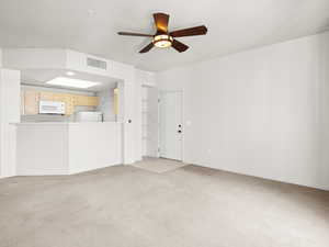 Unfurnished living room with ceiling fan and light carpet