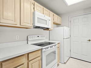 Kitchen with light brown cabinets and white appliances