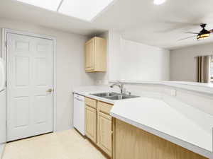 Kitchen with dishwasher, light brown cabinets, ceiling fan, and sink