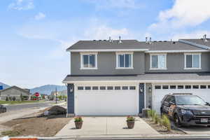 View of property with a mountain view, a garage, and central AC unit