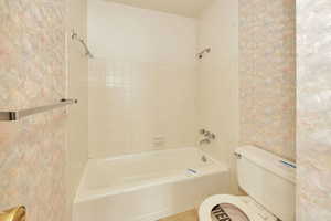 Bathroom with tiled shower / bath and toilet