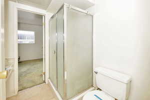 Bathroom featuring tile patterned flooring, toilet, and a shower with door