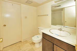 Bathroom with vanity, a shower with shower door, and toilet