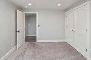 Unfurnished bedroom featuring light carpet and a closet