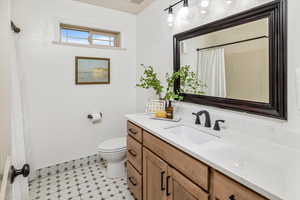 Bathroom featuring vanity, toilet, and curtained shower