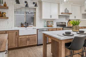 Kitchen with appliances with stainless steel finishes, tasteful backsplash, white cabinetry, and sink