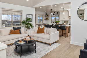 Living room featuring lofted ceiling, light wood-type flooring, and sink