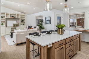 Kitchen featuring a center island, light hardwood / wood-style flooring, pendant lighting, lofted ceiling, and a breakfast bar area