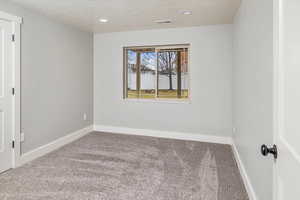 Unfurnished room featuring carpet and a textured ceiling