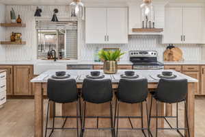 Kitchen featuring white cabinets, stainless steel appliances, a kitchen island, and light hardwood / wood-style flooring