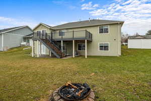 Rear view of house featuring a lawn, a deck, and an outdoor fire pit