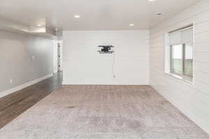 Carpeted spare room with wood walls