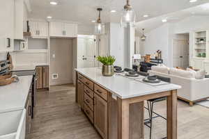 Kitchen with stainless steel electric range oven, a center island, white cabinetry, hanging light fixtures, and lofted ceiling