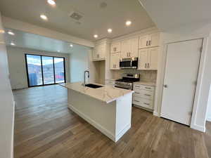 Kitchen with sink, stainless steel appliances, white cabinets, and a center island with sink