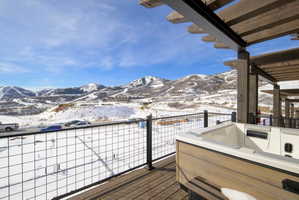 Expansive deck featuring a hot tub, wood-finish flooring, metal grid railing, and a wood pergola