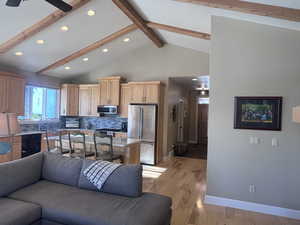 Living room featuring lofted ceiling with beams, ceiling fan, and light hardwood / wood-style floors