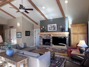 Living room with ceiling fan, beam ceiling, a fireplace, and high vaulted ceiling