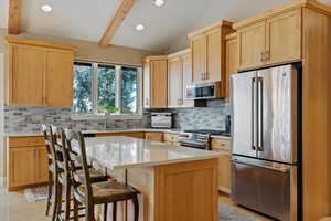 Kitchen featuring appliances with stainless steel finishes, a center island, light brown cabinets, and sink