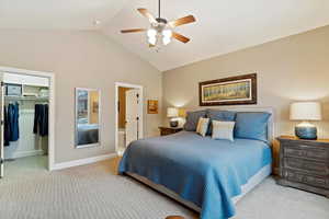 Bedroom with light carpet, ensuite bathroom, ceiling fan, high vaulted ceiling, and a closet