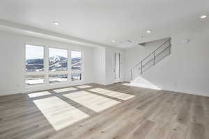 Unfurnished living room with a mountain view and light hardwood / wood-style floors