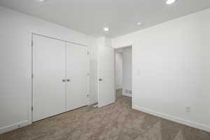 Unfurnished bedroom featuring light colored carpet and a closet