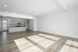 Unfurnished living room with beamed ceiling and light wood-type flooring