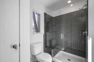 Bathroom featuring a shower with shower door and toilet