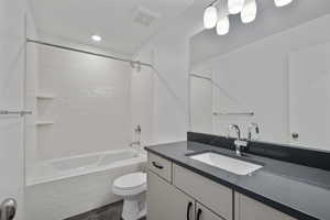 Full bathroom featuring tile patterned floors, vanity, tiled shower / bath, and toilet