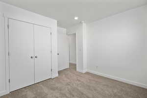 Unfurnished bedroom featuring light colored carpet and a closet