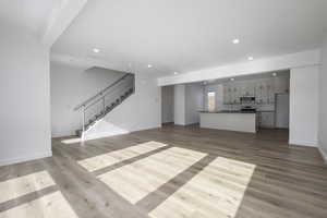 Unfurnished living room featuring sink and light hardwood / wood-style floors