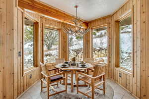 Dining area featuring a chandelier, light tile patterned floors, a textured ceiling, and a healthy amount of sunlight