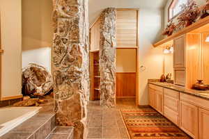 Bathroom with vanity, wooden walls, and a bathing tub