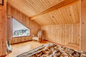 Bonus room featuring beam ceiling, light wood-type flooring, wooden ceiling, and wooden walls