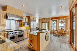 Kitchen featuring built in appliances, light brown cabinetry, and wooden walls