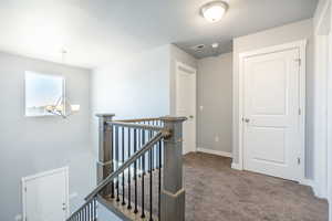 Hallway featuring carpet and a notable chandelier