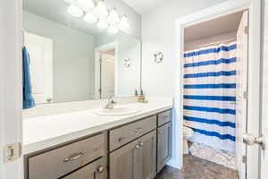 Bathroom with vanity, toilet, and curtained shower