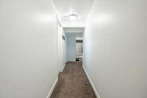 Corridor featuring dark carpet