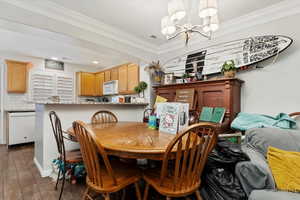 Dining room featuring dark hardwood / wood-style floors, crown molding, and a chandelier