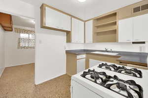 Kitchen featuring white cabinetry, sink, and white gas range oven