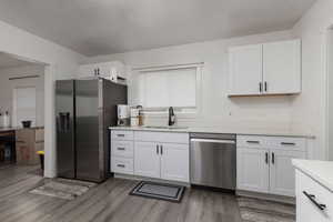 Kitchen featuring white cabinets, stainless steel appliances, light hardwood / wood-style flooring, and sink