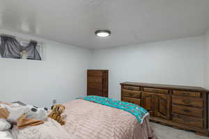 Bedroom featuring light carpet and a textured ceiling