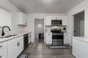 Kitchen featuring stainless steel appliances, white cabinetry, and sink